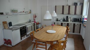 A modern kitchen with a wooden dining table, white cabinets, and a microwave.