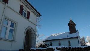 A white building with a stone archway and a small tower with a spire.
