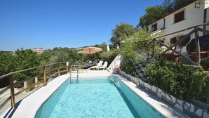 A swimming pool with a stone mosaic design, surrounded by a wooden deck and a stone wall. - DOLCI COLLINE Villa on the hills - POOL, 50min from ROME (Moricone)