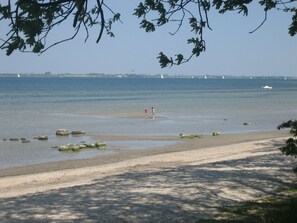 A beach with clear water, rocks, and a distant view of sailboats. - The child-friendly holiday house starfish ín Zierow at Wismar (Zierow)