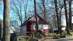 A red house with a white door and windows, surrounded by trees and rocks. - The child-friendly holiday house starfish ín Zierow at Wismar (Zierow)