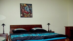 Een slaapkamer met een houten bed, twee nachtkastjes, een wandlamp en een schilderij aan de muur.
