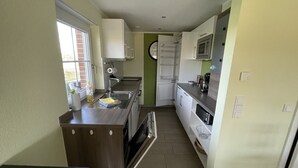 A compact kitchen with a sink, stove, microwave, and cabinets. - LandHausFewo 9a for 5 friends with baby / dog in a secluded rural location (Greven)