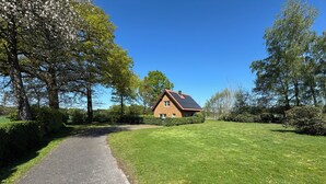 A house with a paved driveway, surrounded by a well-maintained lawn and trees. - LandHausFewo 9a for 5 friends with baby / dog in a secluded rural location (Greven)