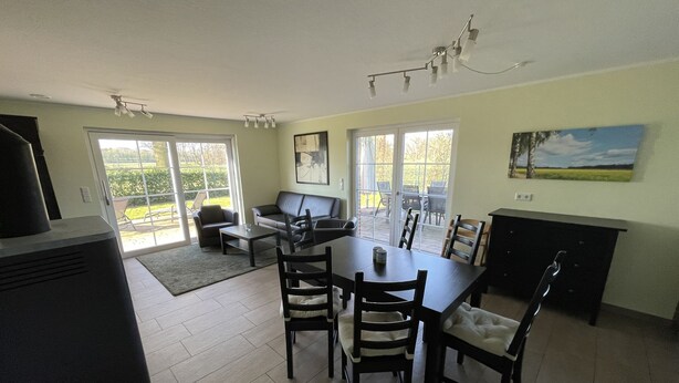 A dining area with a table and chairs, a sofa, and a grill. - LandHausFewo 9a for 5 friends with baby / dog in a secluded rural location (Greven)