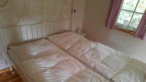 A bed with a white headboard and a bedside table with a clock.