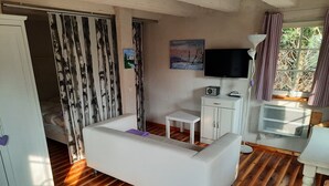 A room with a white sofa, a small white table, a TV, and a cabinet.