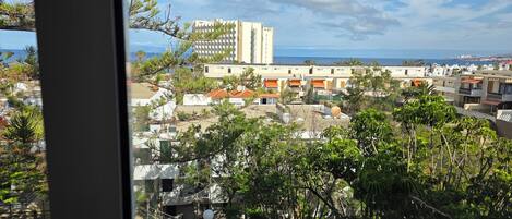 A coastal residential area with a mix of modern and traditional architecture, including a prominent white building with vertical lines and a taller structure with a grid-like facade.