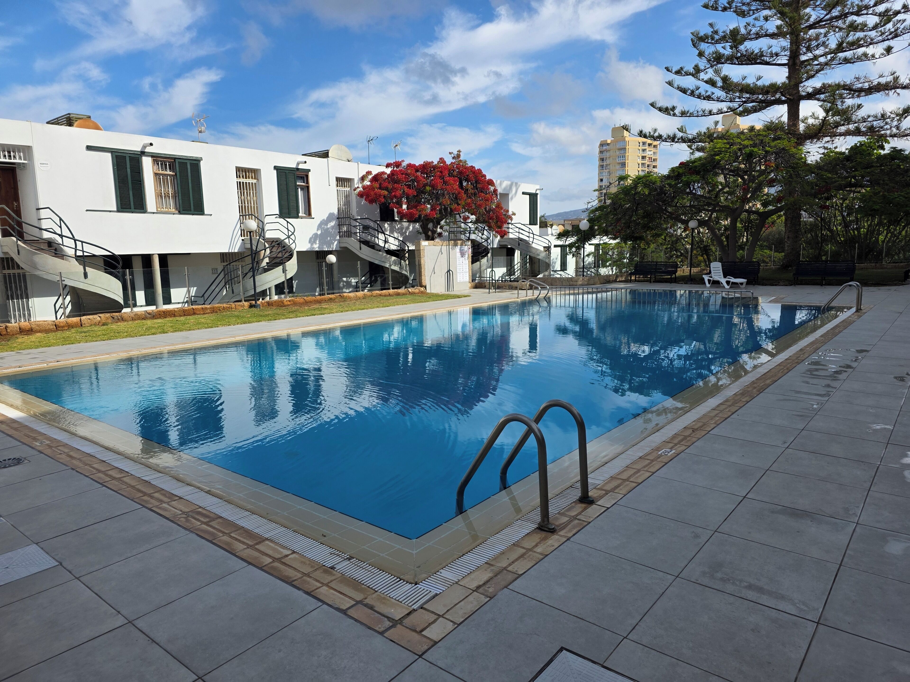 Una piscina con superficie de agua azul cristalina, rodeada por una solana con azulejos.