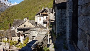 A rustic village with stone buildings, wooden balconies, and a mountainous backdrop.