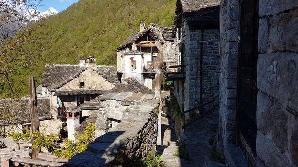 Un village pittoresque aux bâtiments en pierre, aux balcons en bois et dominé par un paysage montagneux.