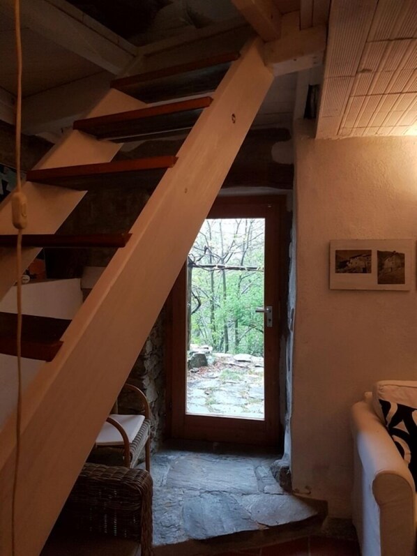 Eine Holztreppe führt zu einer Tür mit Blick auf einen Wald.