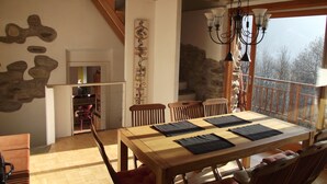 A dining area with a wooden table and chairs, a stone wall, and a view of the outdoors.
