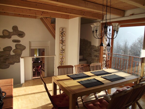 A dining area with a wooden table and chairs, a stone wall, and a view of the outdoors. - Old country house in breathtaking beautiful mountain landscape (Montescheno)