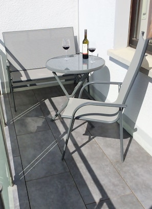 A small outdoor patio with a round glass table, two metal chairs, and a bottle of wine. - Maisonette charming apartment, near bike and. Hiking trails in the Nassau / Limburg nature park (Altendiez)