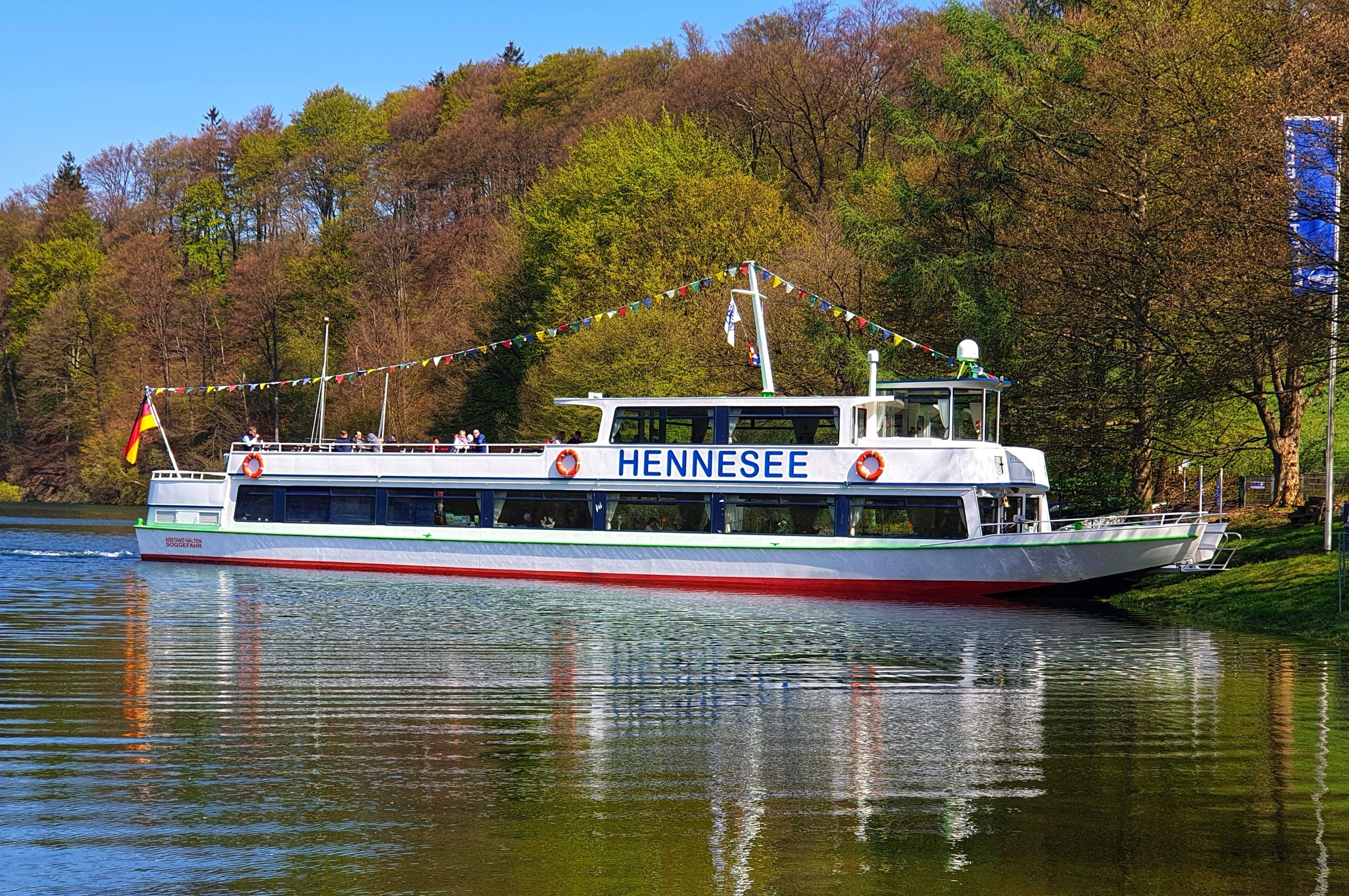 A riverboat named HENNESEE with a white and green color scheme, life rings on deck, and a row of windows.