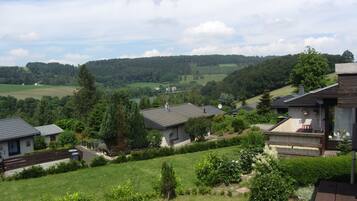 Ein Wohngebiet mit Häusern, umgeben von Grünflächen und einem See im Hintergrund.