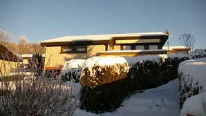 Een woonhuis met twee verdiepingen, een met sneeuw bedekte dak en een schotelantenne.