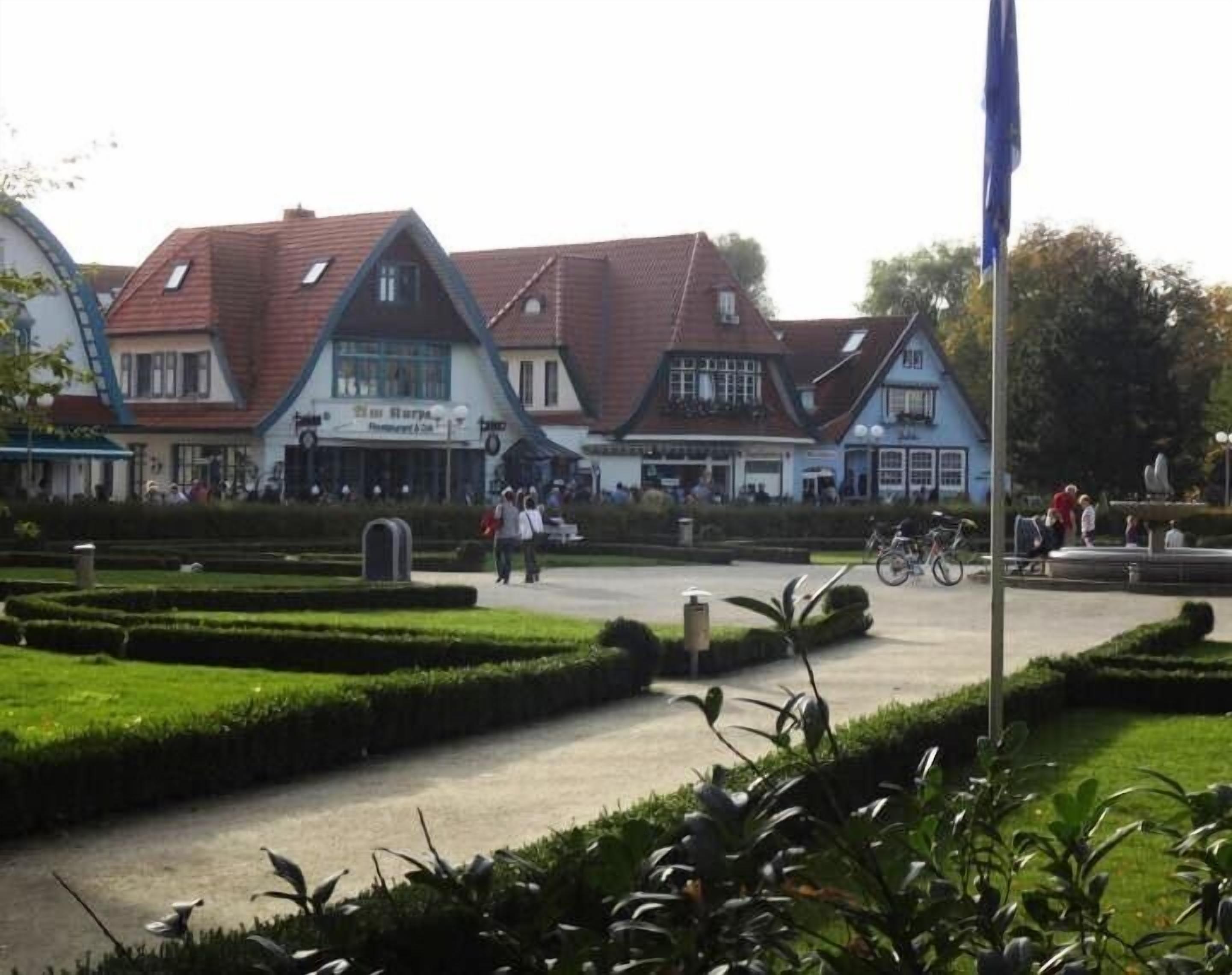 Een klassiek Europees gebouw met een pubbord, omgeven door verzorgde tuinen en een duidelijke looppad.