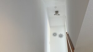 Eine HolztTreppe mit weißen Wänden und einer Decke mit einer Lampe.