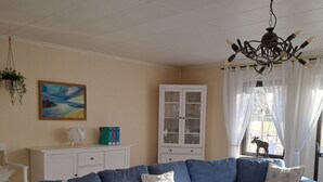 A living room with a sectional sofa, a white cabinet, a painting, and a chandelier.