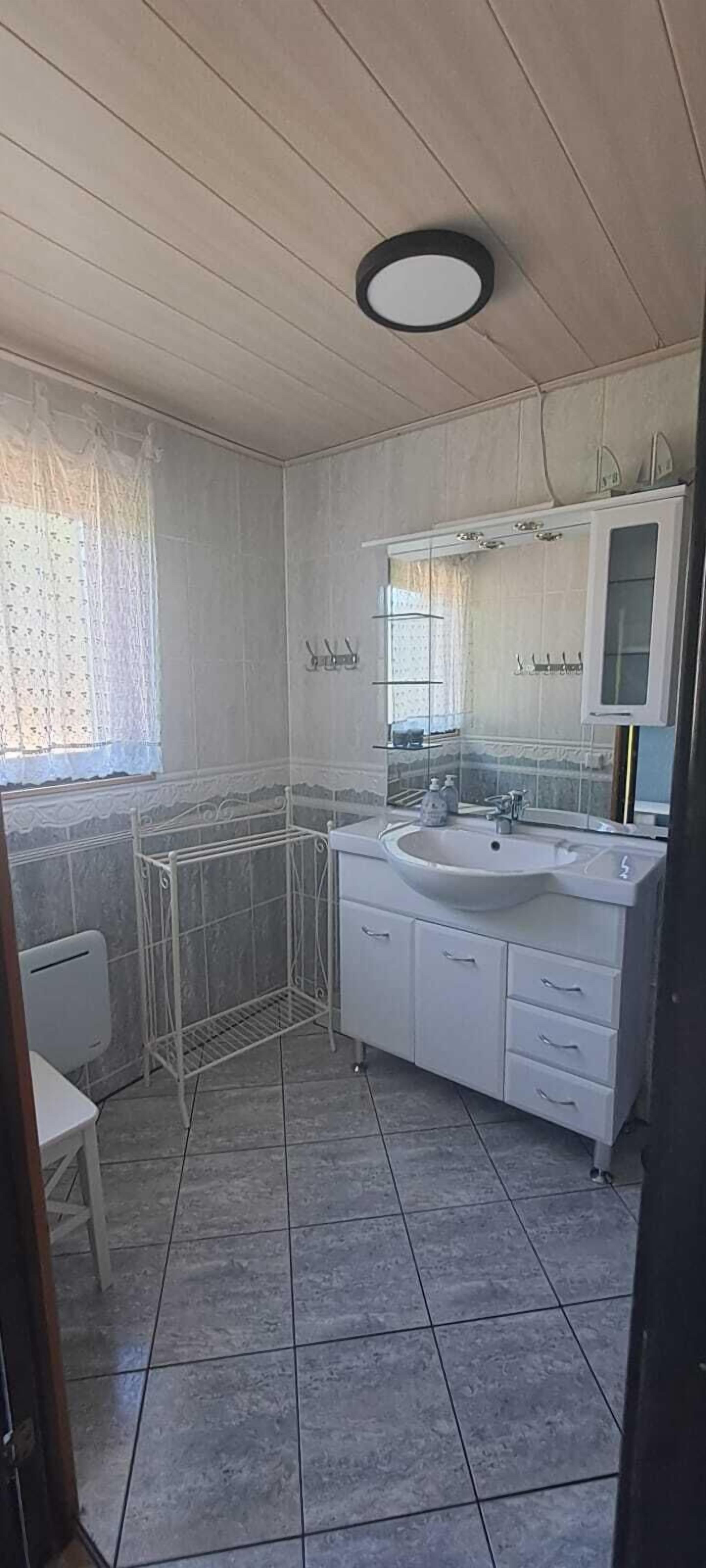 Une salle de bain avec un lavabo blanc, un miroir et un sol carrelé.