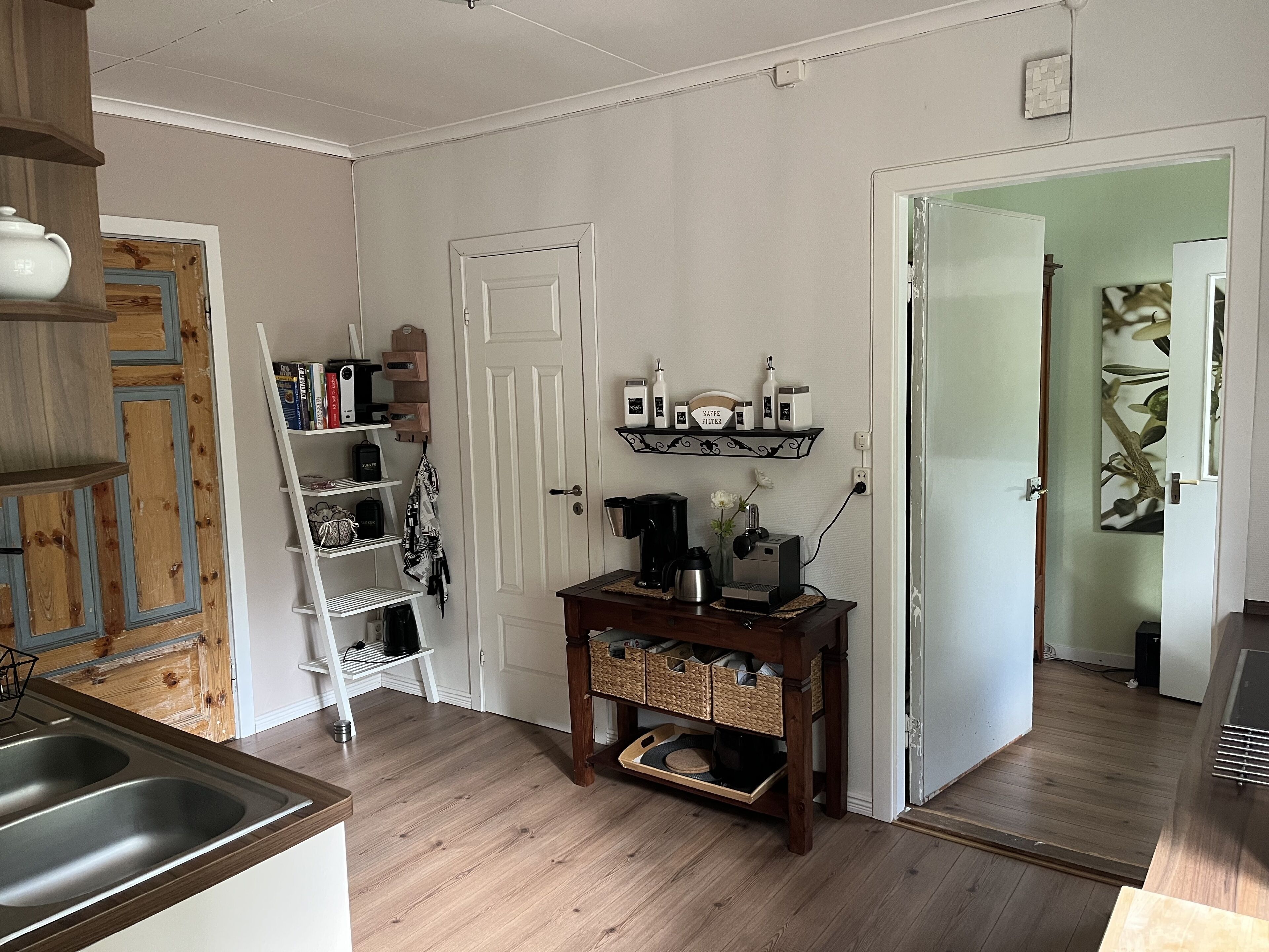A kitchen with a wooden countertop, a coffee maker, and a shelf with kitchen items.