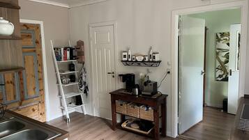 A kitchen with a wooden countertop, a coffee maker, and a shelf with kitchen items.