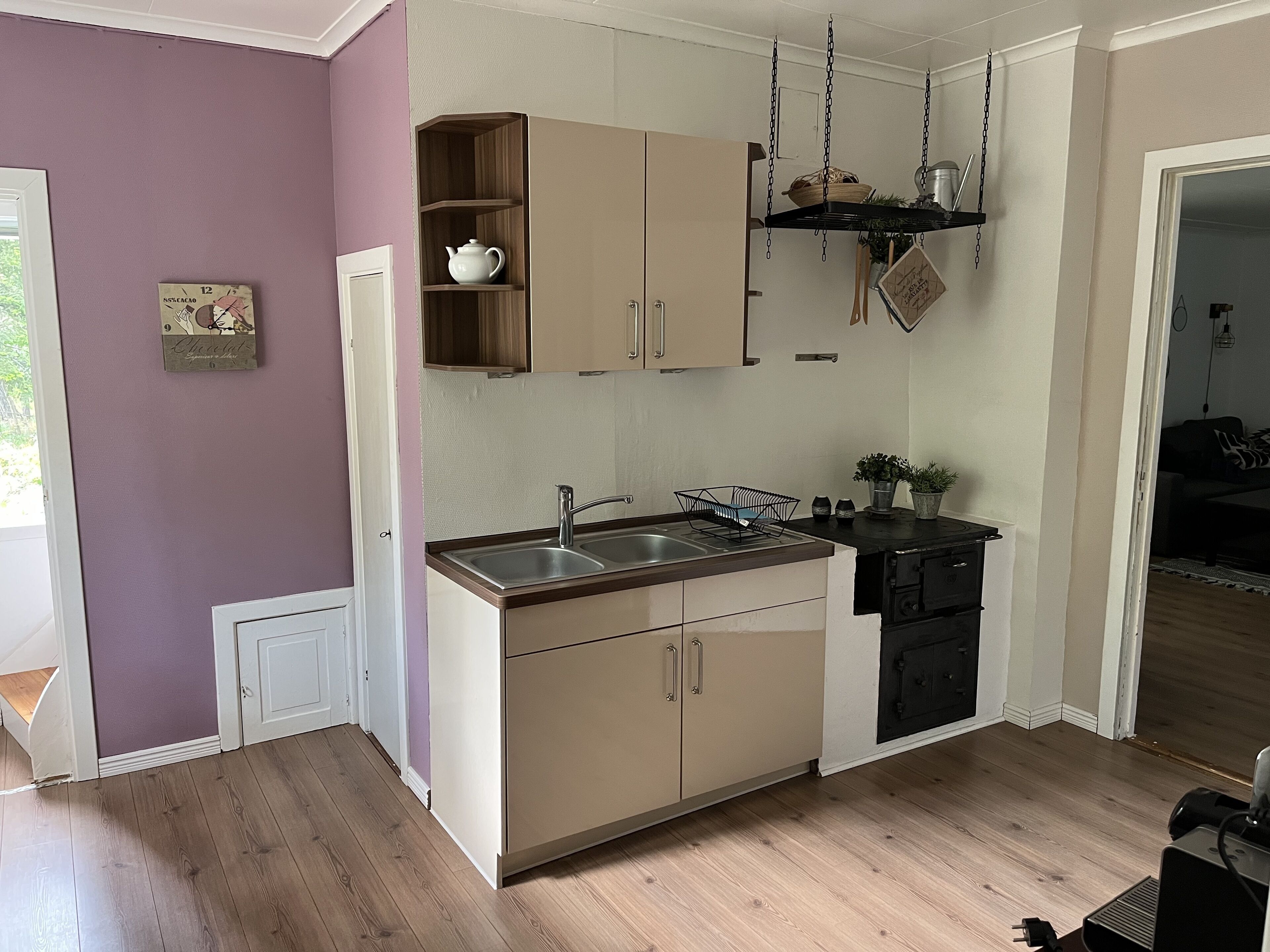 Een kleine keuken met een spoelbak, kastjes en een hangplank.