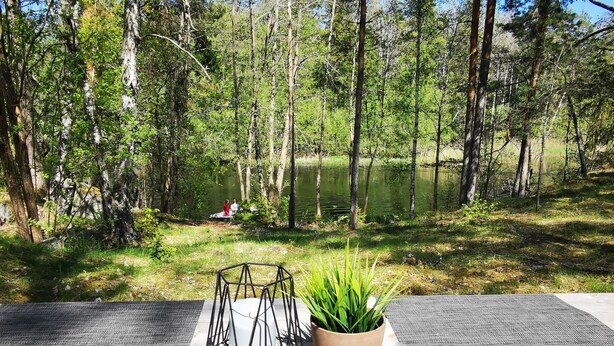 Une terrasse en bois avec une table agrémentée d’un élément décoratif central en métal aux motifs géométriques et d’une plante en pot.