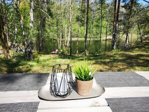 Una terraza de madera con una mesa que presenta una pieza decorativa metálica geométrica y una planta en maceta.