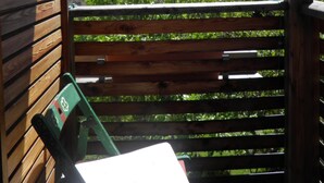 Una terrassa de fusta amb una banca i una cadira, amb vista a un paisatge muntanyós.