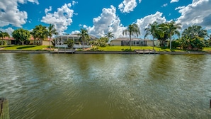 A waterfront property with a large house, a covered patio, and a swimming pool.