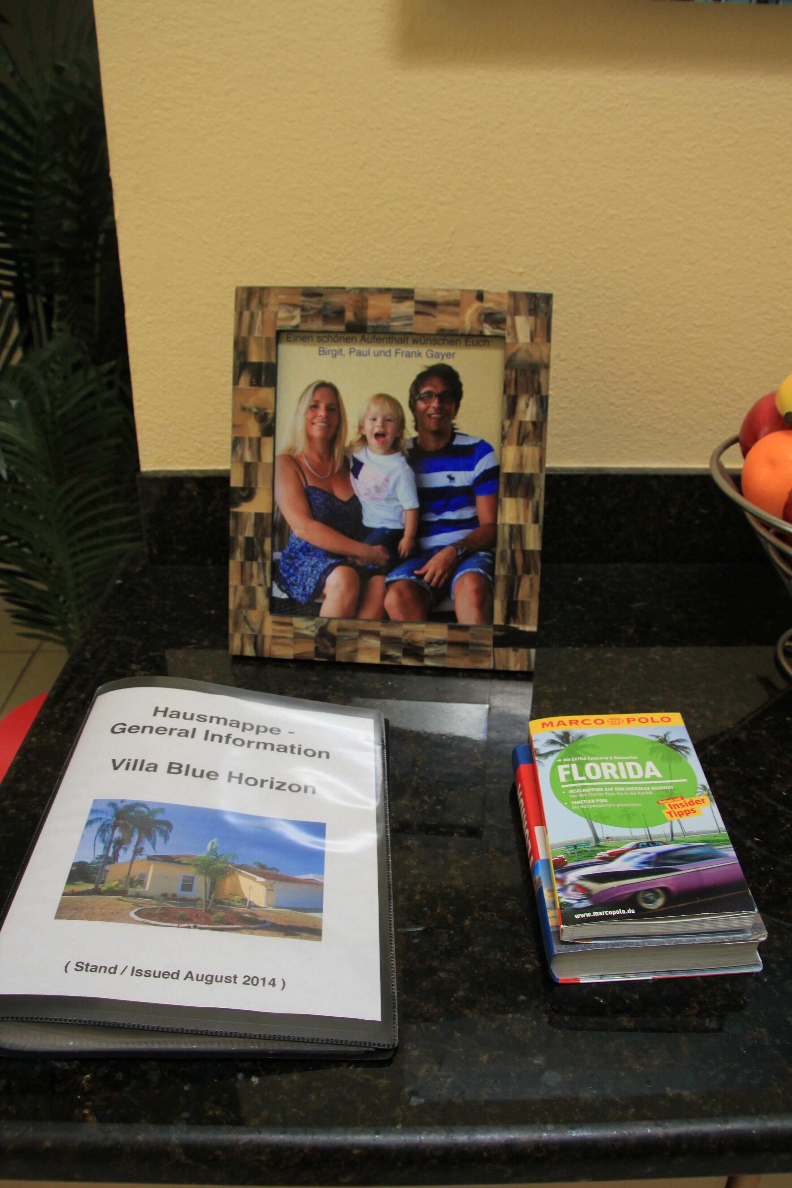 A framed photo of a family, a map of Villa Blue Horizon, and a book titled "Marco Polo Florida" on a counter.