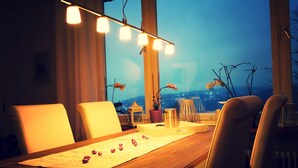 Un comedor con una mesa de madera, sillas y vistas panorámicas de la ciudad a través de amplios ventanales.