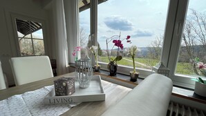 Una habitación con vistas a un paisaje verde, una mesa con una bandeja, una silla y un radiador.