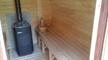 Una sauna con calentador negro, banco de madera y pared de madera.