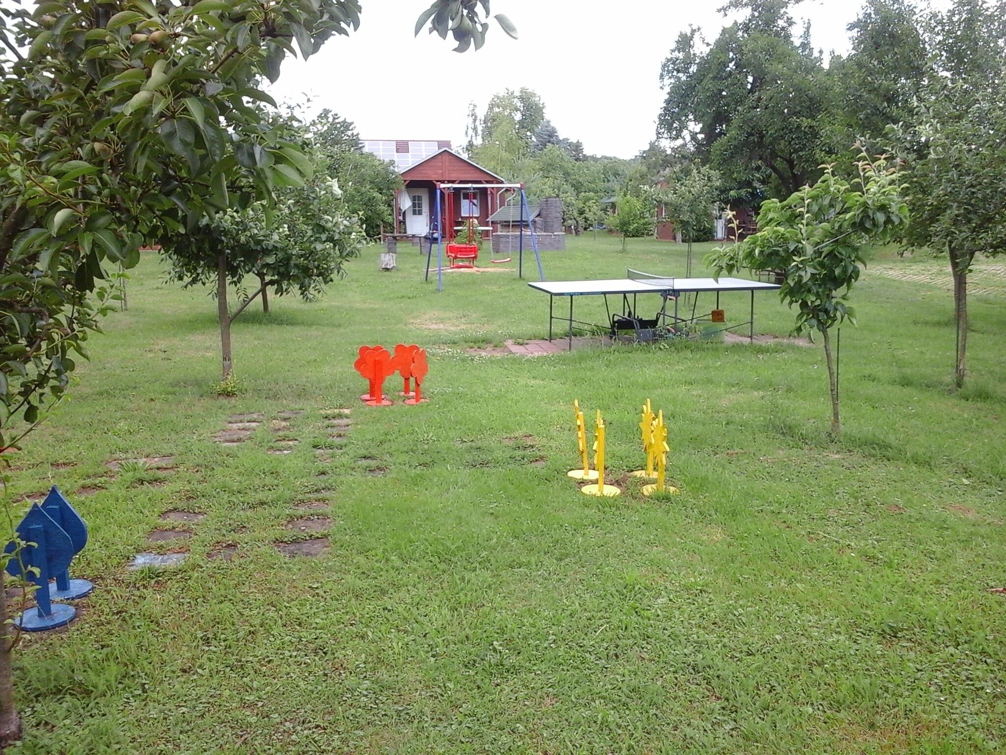A grassy outdoor area with a small building, a table, and some trees.