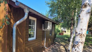A wooden house with a window and a visible air conditioning unit. - 7 vacation homes ideal for family reunions not far from the Spreewald. (Lübbenau/Spreewald)