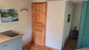 A room with a wooden door, a painting of a landscape, a small table, and a green object on a shelf. - 7 vacation homes ideal for family reunions not far from the Spreewald. (Lübbenau/Spreewald)