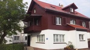 A two-story house with a red roof and white walls.