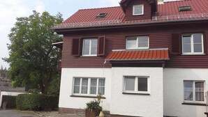 A two-story house with a red roof, white walls, and multiple windows.