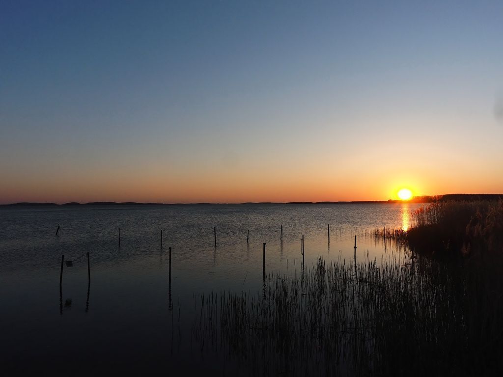 A sunset over a calm body of water with a distant shoreline.
