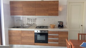 Une cuisine avec des meubles de rangement en bois, une cuisinière à gaz, une machine à café et un évier.
