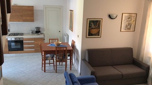 Un espace de vie compact comprenant un coin repas, une kitchenette et un canapé.