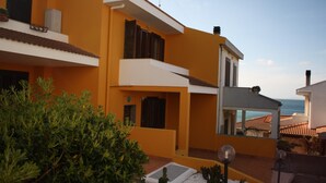 Un bâtiment moderne à la façade jaune, doté de nombreux balcons et offrant une vue sur la mer.
