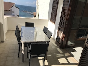 Un balcon avec une table et des chaises, donnant sur une zone côtière.