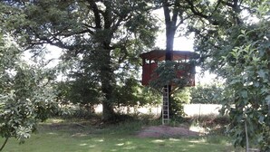 Una estructura tipo casa del árbol construida sobre un árbol grande, con una escalera que lleva a ella.