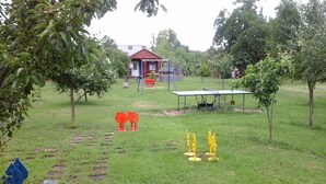 Un espacio al aire libre con césped, un edificio pequeño, una mesa y algunos árboles.