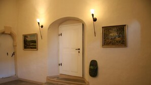 A hallway with a white door, two wall-mounted lights, a bench, and two framed pictures. - Apartment in historic surroundings (Müglitztal)